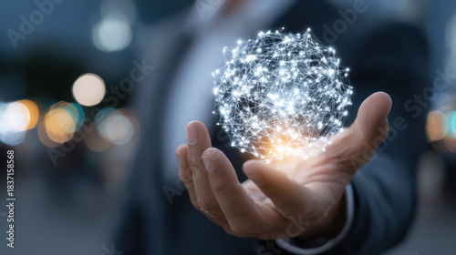 a businessman's hand holding a glowing orb with interconnected nodes inside, symbolizing network or strategy, dark blurred background with bokeh lights