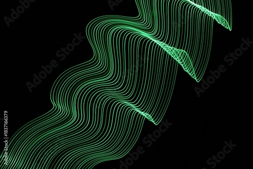 Long exposure light painting photography. Swirls of green light in parallel lines against a black background