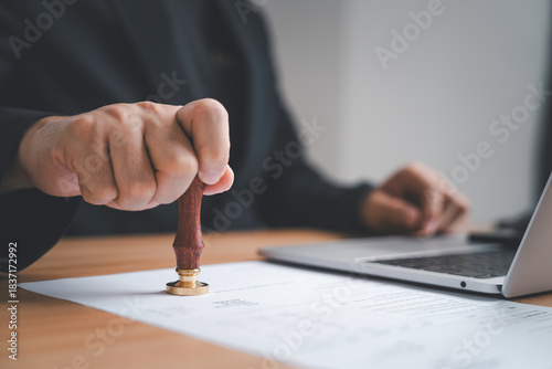 Foto Businessman hand pressing a seal stamp on a document symbolizing authorization v