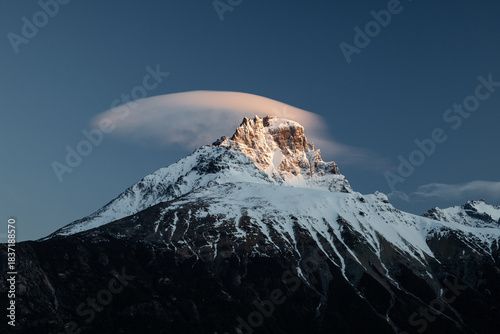 Cerro Castillo Mountain in Southern Chile, Patagonia, rise against blue sky with clouds during early evening in a remote area of nature showcasing a dramatic rocky peak and natural features