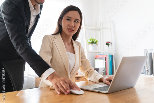 Fényképezés Disgusted asian young employee, pressure business woman uncomfortable, looking hand of boss or colleague when touching her shoulder, embrace