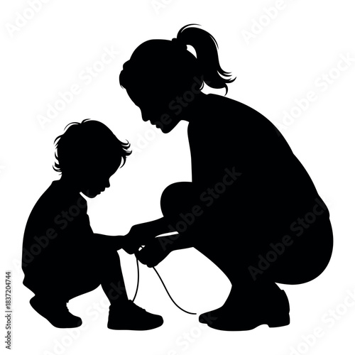 Mother teaches her young child how to tie shoelaces in a silhouette.