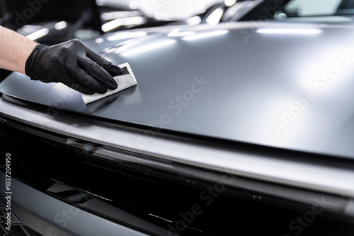 Close-up of ceramic coating being applied to a matte car paint surface by a gloved detailer, showing careful technique, surface protection and professional car detailing dedicated to matte finishes.