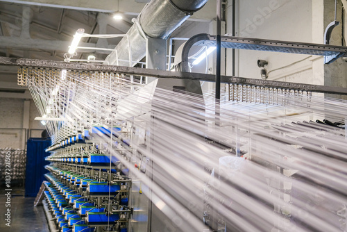 There are many large spools of white thread on the shelves, which are used in textile production