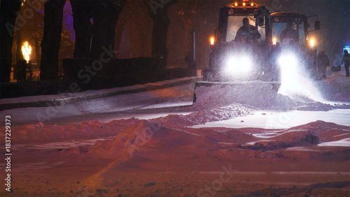 Large snow tractor at work on the evening streets of the city