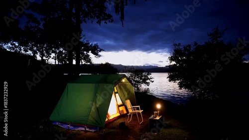 Nighttime forest campsite with a tent glowing under the dark sky