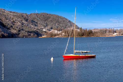 Rotes Segelboot auf dem Schliersee, Bayern, im Winter