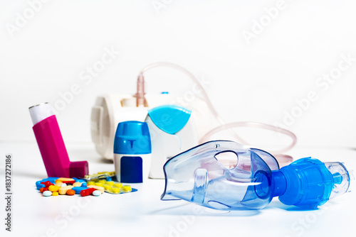 Face mask of modern nebulizer on white table. Equipment for inhalation, close-up, selective focus, white background. Asthma breathing treatment. Bronchitis, asthmatic health equipment.