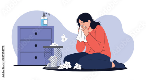 Sick young woman with a cold or flu sits on the floor blowing her nose surrounded by used tissues and hand sanitizer.