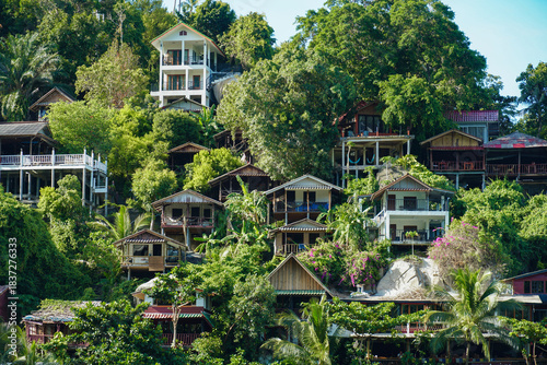 View on the Than Sadet beach,koh Phangan island,Thailand. Tropical beach shore in Koh Phangan with huge rocks, coconut palm tree, lush green vegetation and small steps leading to tourist bungalows.
