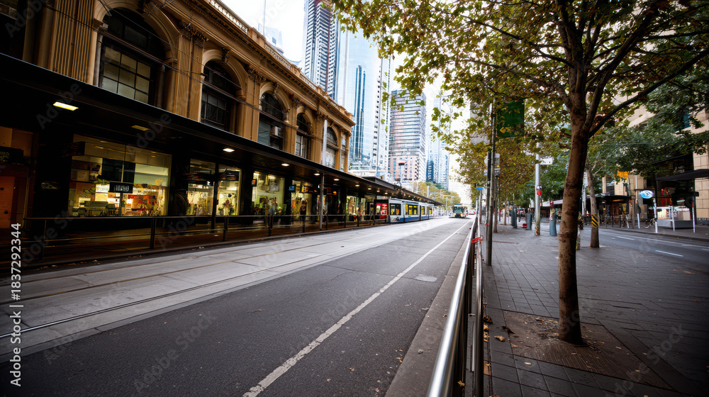 Fototapeta premium A tranquil city street scene reveals a heritage building, sleek modern skyscrapers, and a glimpse of public transport on a quiet day in the urban landscape.