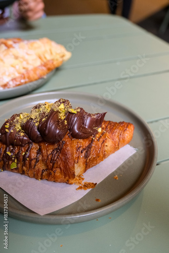 Chocolate topped croissant served on a plate, showcasing artisanal bakery products, café lifestyle, and modern dessert presentation. Publique bakery, popular tourist destination in Melbourne