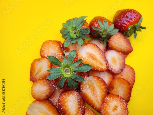 Many pieces of delicious strawberries against a yellow background