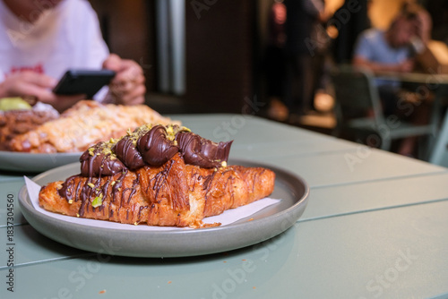 Chocolate topped croissant served on a plate, showcasing artisanal bakery products, café lifestyle, and modern dessert presentation. Publique bakery, popular tourist destination in Melbourne