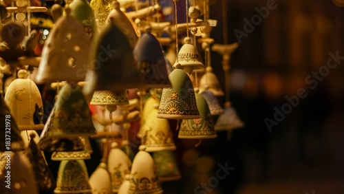 A cozy display of handmade ceramic bells with intricate blue patterns hangs in warm light at a Christmas market. Perfect for festive decor, crafts, and gift inspiration this season ahead.