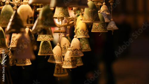 A cozy display of handmade ceramic bells with intricate blue patterns hangs in warm light at a Christmas market. Perfect for festive decor, crafts, and gift inspiration this season ahead.