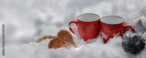 two red mugs with wooden heart shaped in the snow in blur white - valentine concept