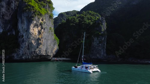 Yachting in Thailand, relaxing at sea during an island hopping trip. A sailing yacht against a backdrop of shaded limestone cliffs, a beautiful picture of a yacht vacation in Southeast Asia.
