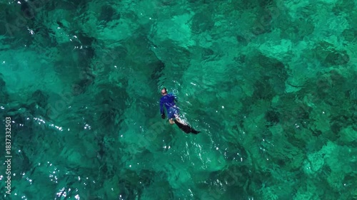 Vacation in Southeast Asia, sea travel in Thailand. Snorkeling near tropical islands. A man exploring the underwater world off the coast of Racha Yai Island, as seen from a drone.