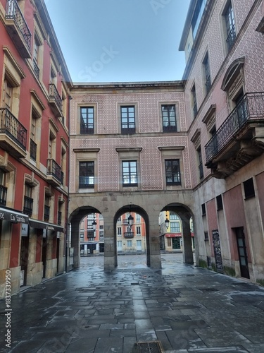 Main square of the tourist city of Gijon with its classic buildings and stone arches surrounding the square, Asturias.
