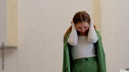 High school student in white turtleneck and green blazer performs song and simple dance moves at school stage audition, trying to get a role in the theatre play.