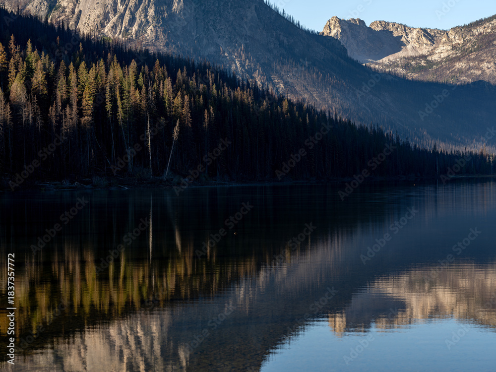 Fototapeta premium Intimate reflection of forest at sunrise in mountain lake