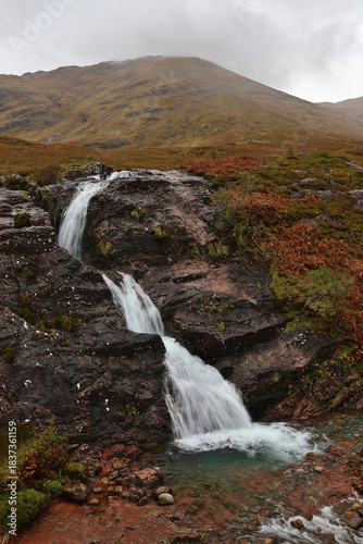 Glencoe Waterfall in the Scottish Highlands; running water in Scotland mountain scene with autumn colours on the hills