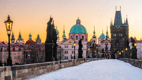 Canvas Print The UNESCO world heritage site Charles Bridge covered in snow with shining lamps in Prague in the winter morning dawn