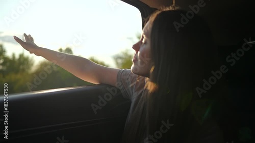 Woman enjoys trip hand out car window. beams through window she feels breeze. Carefree road trip adventure filled with freedom. Joyful car journey embracing freedom. Open road brings peaceful freedom.