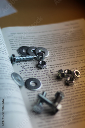 Metal bolts, nuts and washers on open book