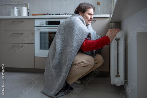 Foto Freezing man wrapped in blanket sits by heater trying warm in bad heated apartment
