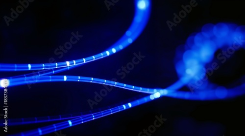 Neon blue abstract light lines flowing across dark background. Luminous blue strands dance in motion, creating mesmerizing patterns and effects.