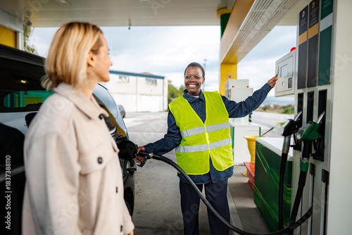 Attendant serving customer refilling car at gas station