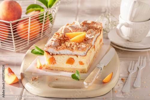 Fresht and sweet peach cheesecake served on white kitchen.