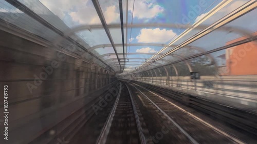 POV from a metro train driver cab on outdoor section, between stations with fast motion rails and city scenery creating an immersive urban transportation ride