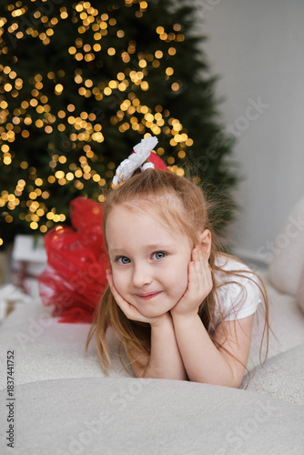 Girl enjoying Christmas spirit by beautifully decorated tree with glowing lights