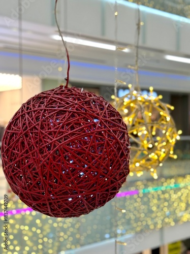 Close-up of a large red wicker Christmas ornament with glowing string lights inside. Festive holiday decor element for winter, New Year, and Christmas-themed designs