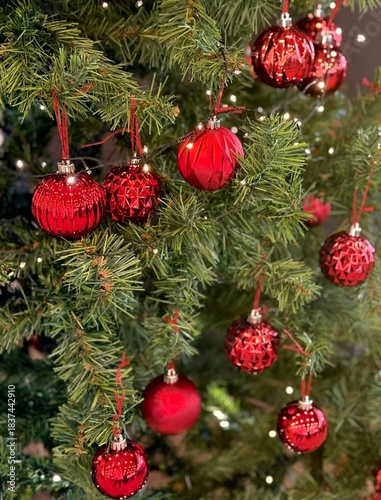 Close-up macro view of a Christmas tree decorated with shiny red baubles and festive lights. Perfect for Christmas, holiday, winter and seasonal design projects