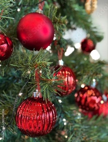 Close-up macro view of a Christmas tree decorated with shiny red baubles and festive lights. Perfect for Christmas, holiday, winter and seasonal design projects