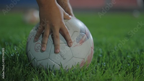 A footballer's hands place the ball on the turf of a football field before a shot
