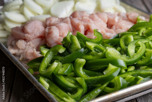 Sheet pan chicken fajitas with sliced onions, green bell peppers, and seasoned chicken arranged on a baking tray. Fresh, simple, and perfect for meal prep or easy dinner recipes.