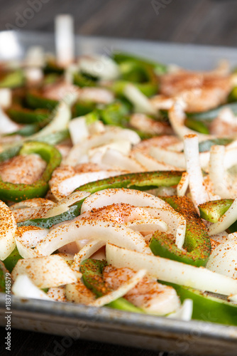Sheet pan chicken fajitas with sliced onions, green bell peppers, and seasoned chicken arranged on a baking tray. Fresh, simple, and perfect for meal prep or easy dinner recipes.