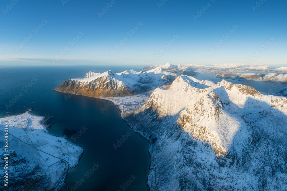 Naklejka premium Flight over the mountains. Scandinavia. Aerial view on the Lofoten Islands, Norway. Wide panoramic view of the north. Natural winter landscape from air. Photo for postcards, backgrounds, wallpapers.