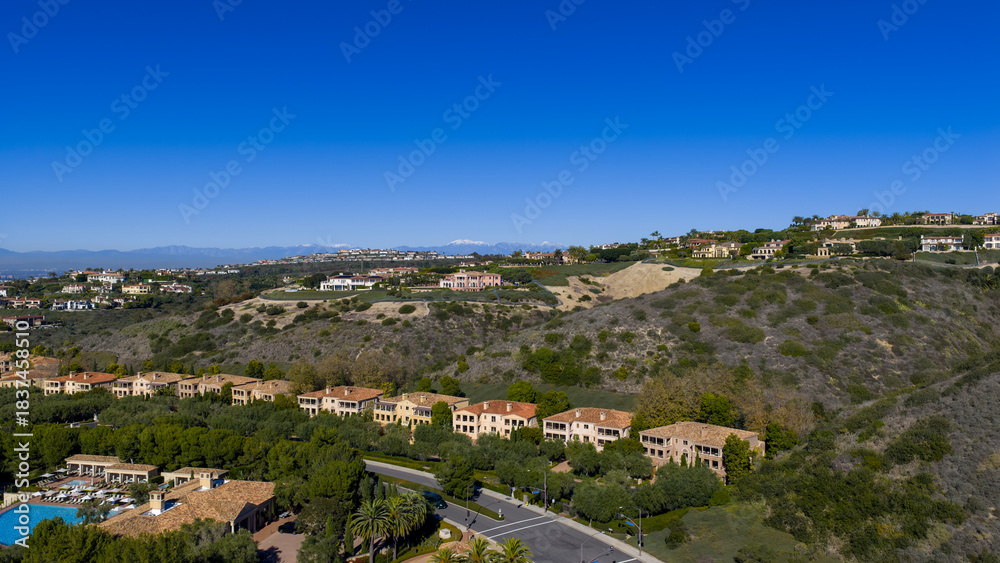 Fototapeta premium Aerial shot of luxury homes, lush green grass and trees at the Pelican Hill Resort in Newport Beach California USA