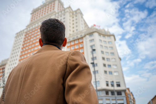Wallpaper Mural Man gazing at historic city building under a bright sky in the heart of the city Torontodigital.ca