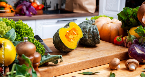 large green pumpkin on wooden kitchen table with fresh autumn vegetables and herbs at cozy seasonal home cooking. Healthy eating, lifestyle, recipe idea concept.