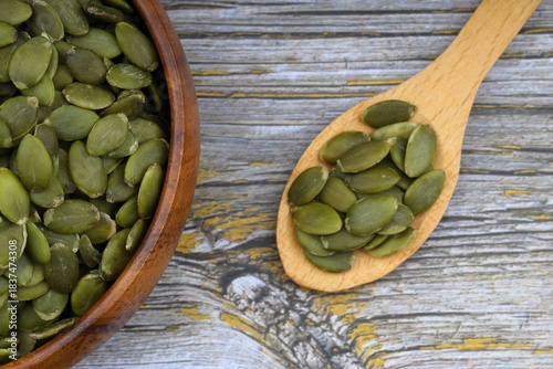 Pumpkin seeds in a wooden bowl on a wooden background