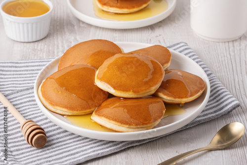 Delicious fluffy pancakes with syrup served on a white plate for breakfast
