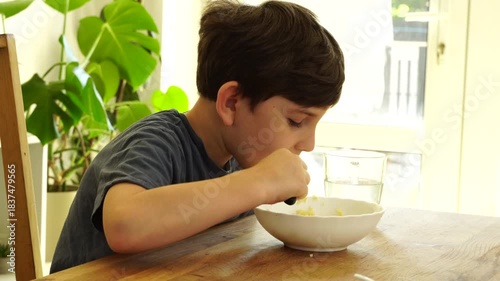 Boy eats noodles at the kitchen