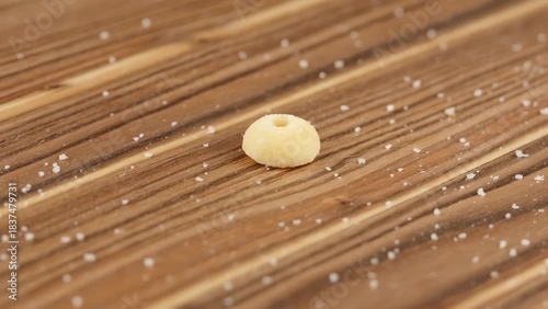 Close-Up of a Single Piece of Pasta on Wooden Surface Surrounded by Salt